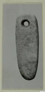 Elongated stone object with a round perforation near one end, photographed against grey card, Nitovikla T.I