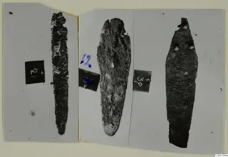Three corroded metal blades from Nitovikla T.I, each on a grey card beside a small number label