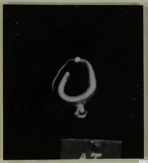 Gold earring with a small pendant from Amathus tombs, photographed against a black background