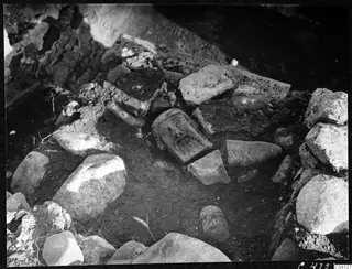 Carved stone head lying among loose stones and fragments at Cholades, Soli