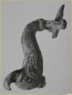 Corroded bronze object with a curved shaft, a flat crosspiece with a pointed spike, and a hooked lower end
