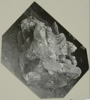 Weathered stone sculpture fragment from Soli, resting on soil.