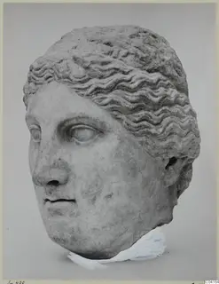Marble head of a woman with wavy hair swept back, shown against a grey backdrop.