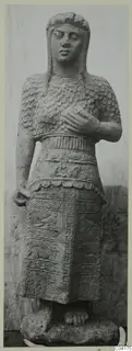 Stone statue of a standing figure from Soli, shown from the front against a pale backdrop