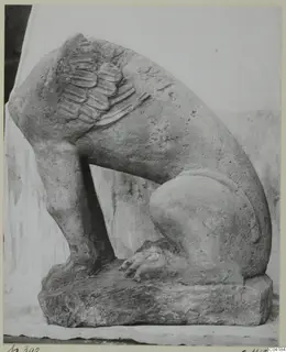 Stone sculpture of a crouching winged animal from Soli, shown against a white cloth backdrop