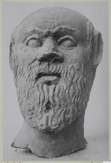Stone head statue from Soli showing a bearded face with a bald crown and wavy curled beard.