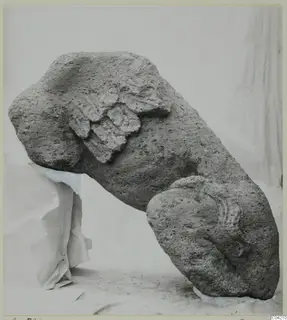 Stone sculpture fragment from Soli, porous grey stone with carved relief, photographed on a white cloth