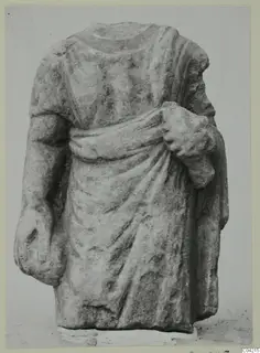 Headless stone statue torso from Soli, wearing a draped garment, one arm bent up holding cloth at the chest.