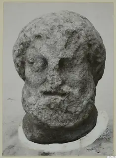 Carved stone head of a bearded man from Soli, photographed frontally against a pale background