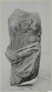 Stone sculpture fragment from Soli showing a draped figure with a band at the waist and an arm wrapped in cloth.