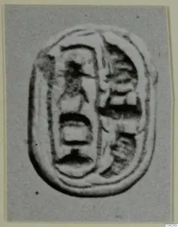 Oval seal or gem with carved signs in two vertical columns, photographed on grey card