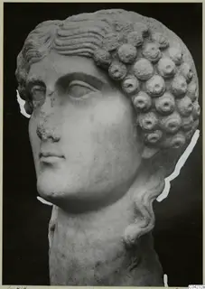 Marble head from Soli with rows of rounded curls, shown against a dark background.