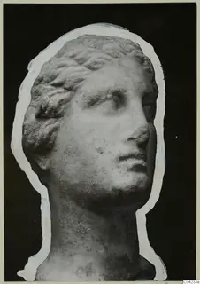 Carved marble female head with wavy hair, turned to the right, shown against a black background