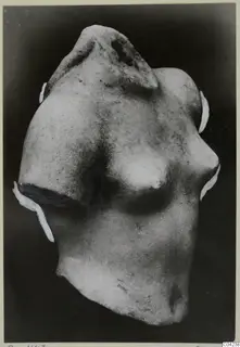 Fragment of a marble sculpture: a torso with a broken neck and shoulder, shown against a dark background