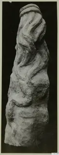 Carved stone sculpture fragment with wavy ridges and a rounded band at the top.