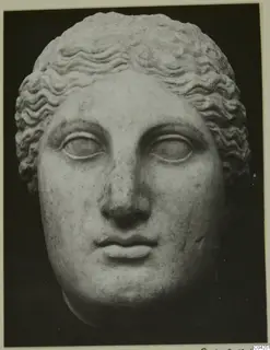 Marble head with wavy hair and large eyes, shown frontally against a dark background.