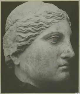 Marble sculpture of a head with wavy hair, from Soli, photographed against a dark background.