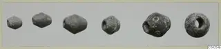 A row of small beads, biconical and rounded, shown side by side on a light photo card
