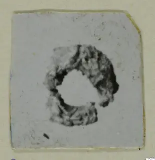 Lead object, a rough ring shape, shown as a small print on a card