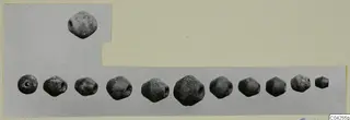 Twelve grey perforated beads, one set above and eleven in a row, on a grey card mount