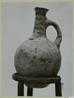 Pottery White Painted IV-V jug from Milia, with a single handle, standing on a metal stand