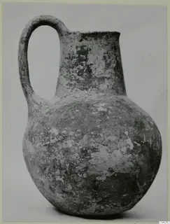 Pottery Black Slip Ware jug with a single loop handle and a rounded body, shown against a plain background