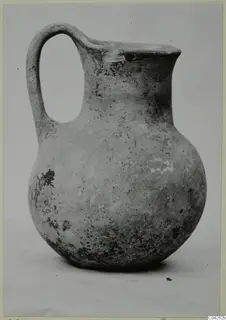 Round-bodied jug with a strap handle and flared rim, photographed against a plain background, from Milia.