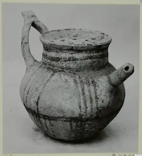 Pottery vessel from Milia with a strap handle, a short side spout and a perforated rim, decorated with dark painted bands