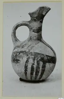 Pottery jug from Milia with a loop handle and dark painted bands on a pale surface