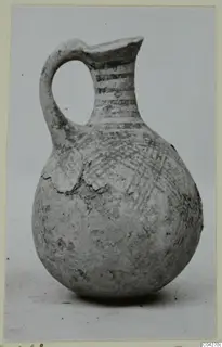 Pottery juglet with a looped handle and painted bands and crosshatching on a rounded body
