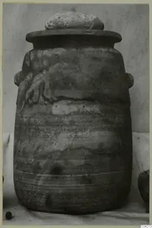 Alabaster vessel from Amathus with a domed lid and side handles, photographed on a cloth against a plain backdrop.