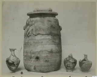 Alabaster vases from Amathus: one large lidded stone jar with two small handles, flanked by three smaller broken vessels
