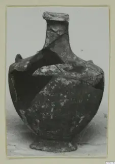 Pottery jar with a narrow neck, rounded body and low foot, pieced together from fragments, shown against a pale background.
