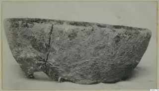Rough grey bowl with a deep crack down one side, shown in side view on a plain background