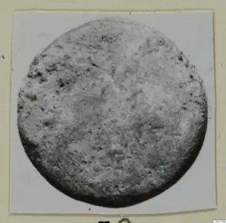 Round, pitted disc-shaped find from Amathus, photographed on a card mount