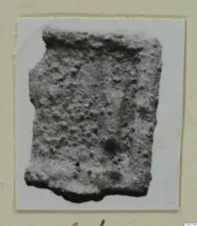 Fragment with a speckled surface from Amathus finds, shown on a pale card mount