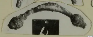 Corroded metal loop-shaped object from Amathus, shown as a cut-out print on a cream card mount