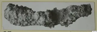 Corroded iron tool from Amathus, shown against a plain light background on a photo mount.