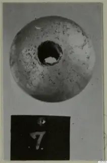 Round object with a large central hole, photographed from above beside a number label, from Amathus tombs