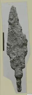 Corroded iron weapon blade from Amathus, leaf-shaped with a tapering tang, shown on a grey card mount.