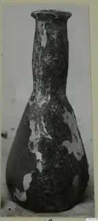 Glass bottle from Amathus with a long neck, flared rim and pear-shaped body, its surface heavily encrusted