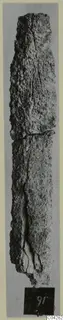 Long corroded iron tool from Amathus, photographed upright against a grey background.