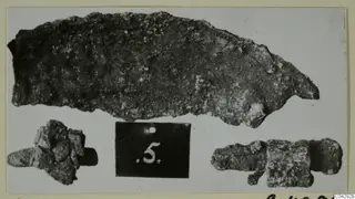 Three corroded metal objects from Amathus, tombs 2–26, photographed beside a dark number label