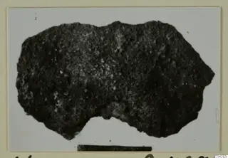 Dark irregular fragment from Amathus T. 2-26, shown on a photo card with a scale bar below