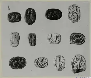 Twelve carved stone seal-shaped objects arranged in three rows, from Arsos, on a grey card