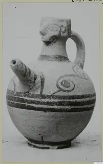 White Painted IV pottery jug with a modelled face at the neck, a side spout, and painted bands and spirals