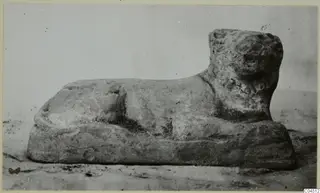 Small recumbent animal figure with a broad head and a rectangular base, seen from the side
