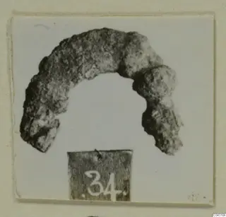 Heavily corroded arc-shaped metal object, a bronze part with a loop, from Amathus