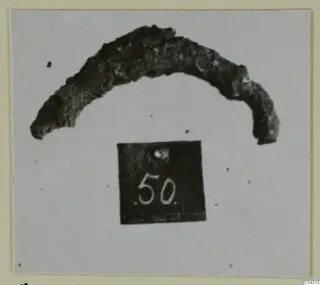 Curved, corroded bronze fragment from Amathus, shown with a number label