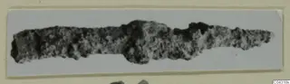 Corroded metal object from Amathus, elongated with a broader bulge near the middle, shown on a card mount.